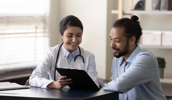 Doctor talking through medical documents with patient
