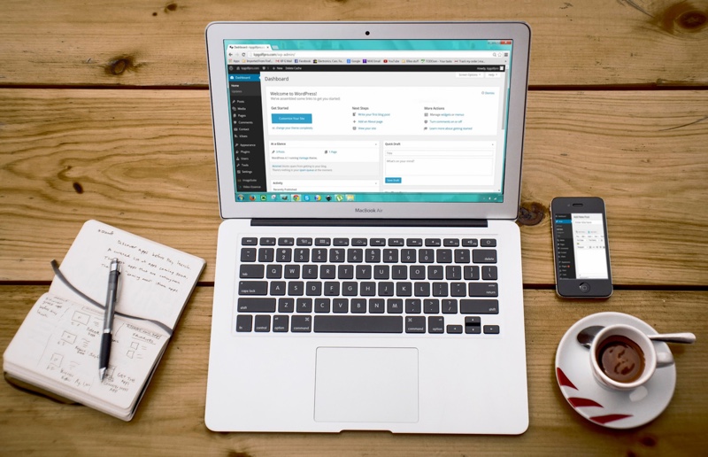 computer next to notebook, mug, and glasses