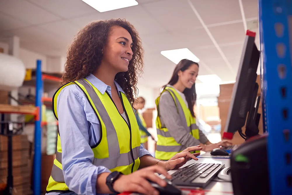 female warehouse workers typing on computers