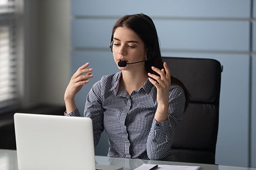 Woman sits at desk with headset