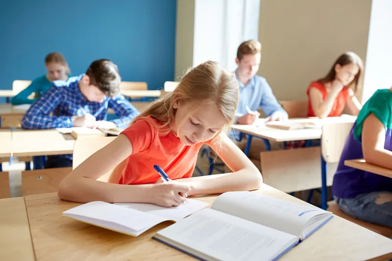 child writing in notebook and reading from textbook